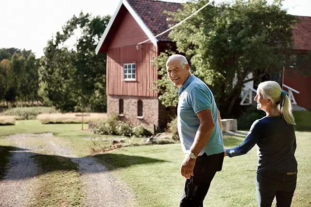 Äldre par framför rött hus