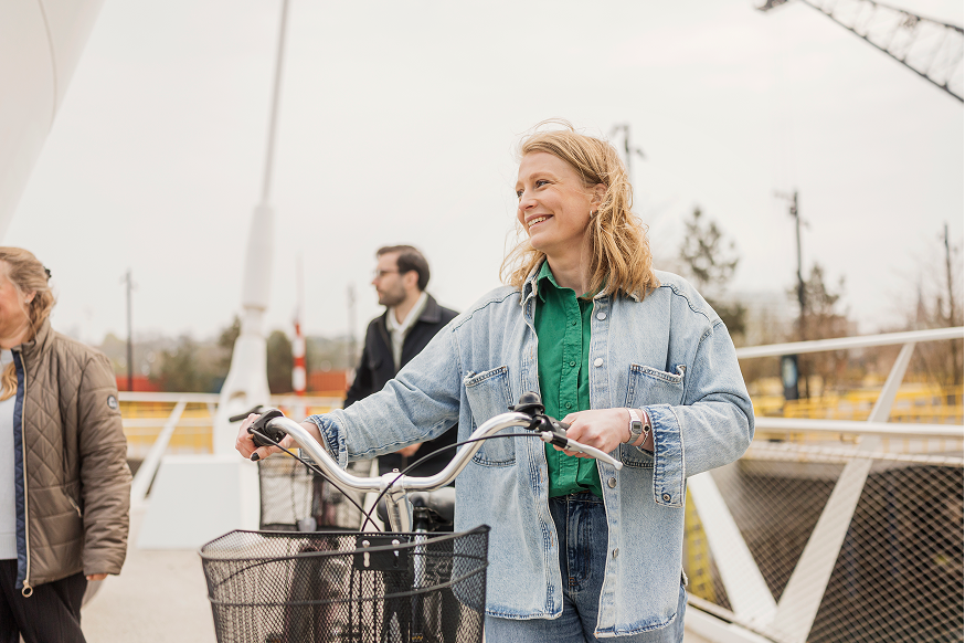 glad kvinna som leder sin cykel över en bro